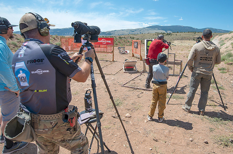 Griffin Cole, of Cheyenne, passes the time prior to his turn on stage 4 of the 10-stage competition watching others compete in long-range and speed events at the Cody Shooting Complex.