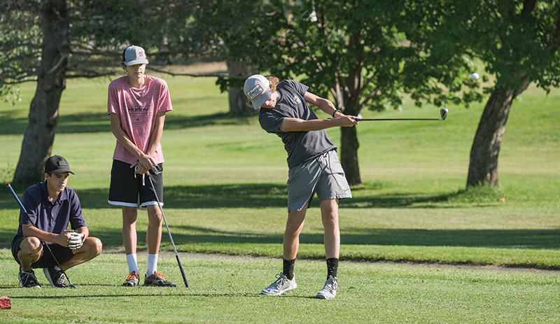 PHS junior Parker Williams hits a tee shot while sophomore Jackson Hill (left) and junior Tevon Schultz look on during practice on Tuesday.