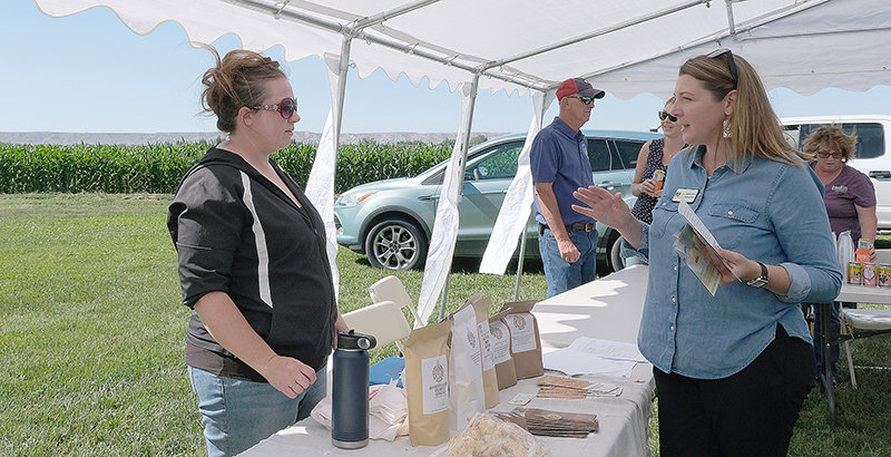 Sara Wood (left), owner of Wyoming Heritage Grains, discusses agriculture with Rebekah Burns, executive director of the Powell Economic Partnership, during the Field Days event in July, at the Powell Research and Extension Center. Wood offered samples of cookies and biscuits made from the heritage grains grown and stone milled on her Heart Mountain farm.