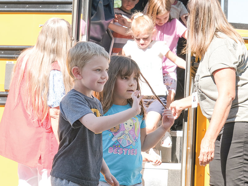 Aaron Waite (left), and Abby Trevino (right) wave confidently after their tutorial bus ride during Kindergarten Jump Start on Wednesday.