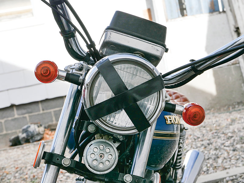 The motorcycle’s headlight has been taped, a characteristic of early cafe racer builds to prevent flying glass if a rock were to shatter the headlight.