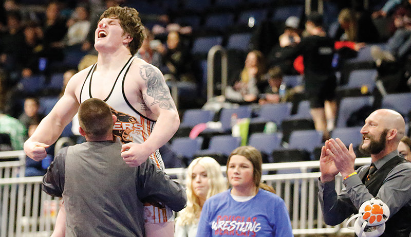 Panther senior Stetson Davis jumps in coach Nick Fulton’s arms after winning the state title at 220 pounds on Saturday night.