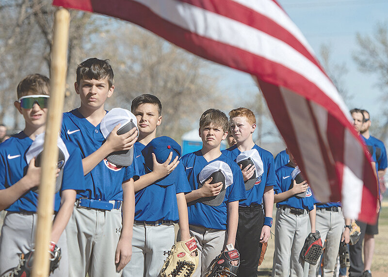 Cubs teammates line up near home plate for the national anthem during opening day ceremonies.