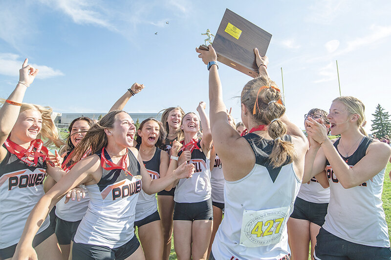 Anna Bartholomew holds up the state championship trophy to the excitement of the rest of Panther girls’ track team after Powell claimed its third straight team title.