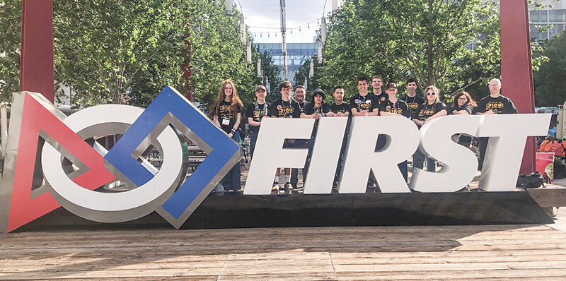 Powell Robotics Team 3189 poses behind the FIRST Logo in Houston, Texas in April. They traveled to the city to compete in the world championships. From left, Kate Miller, Luke Legler, Dexter Opps, coach Joel Hayano, Mason Coombs, Elias Brower, Alan Crawford, Dallin Waite, Brighton Streeter, Nolan Reitz, Isabelle Lobingier, and coaches Lenita Moore and Hans Hawley.