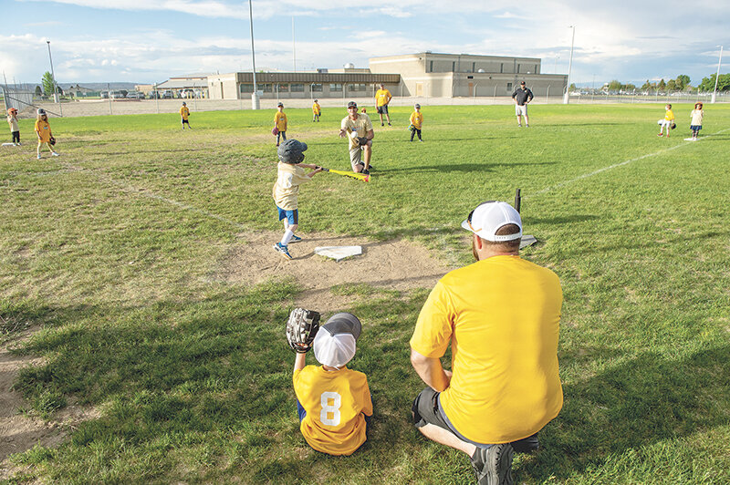 Bananas coach Spencer Fry helps catcher Carson Shuler (8) during their game with the Vibes on Tuesday evening. Coaches pitch a few balls to players before putting out the tee to get children used to hitting.