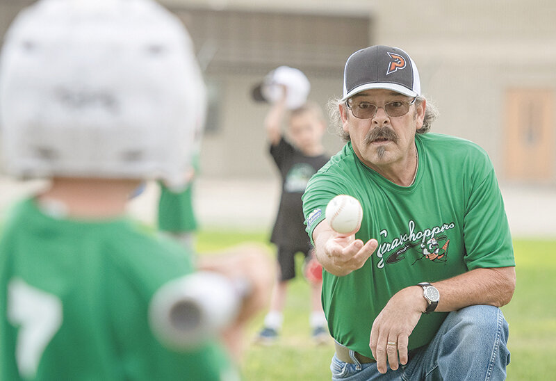 Grasshopper coach Ted Shinn pitches to his players before putting the tee in place. The littlest league uses ‘soft’ balls to keep the children from getting hurt.
