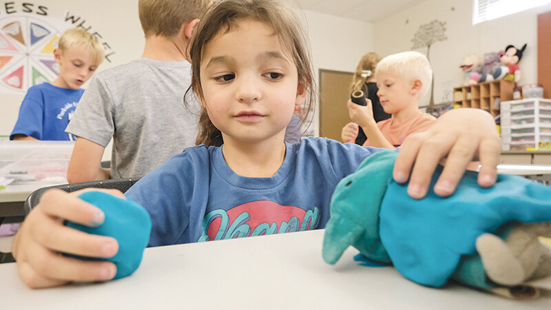 Raegan Varian plays with her stuffed animal, which she has modified with play dough.