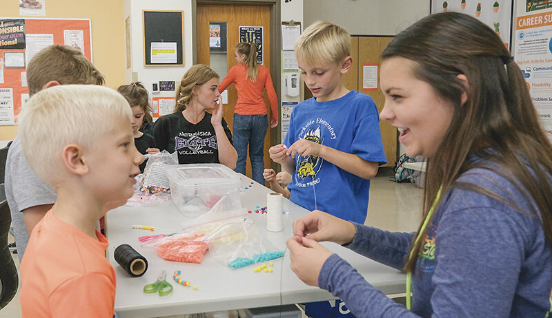 Paxton Rohrer (left) talks with Powell High junior Kendal Eden while she ties the bracelet he made.