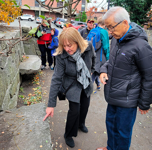 Jill Christiansen, an educator at the Salem Witch Museum, shows Sam Mihara the Salem Witch Memorial.