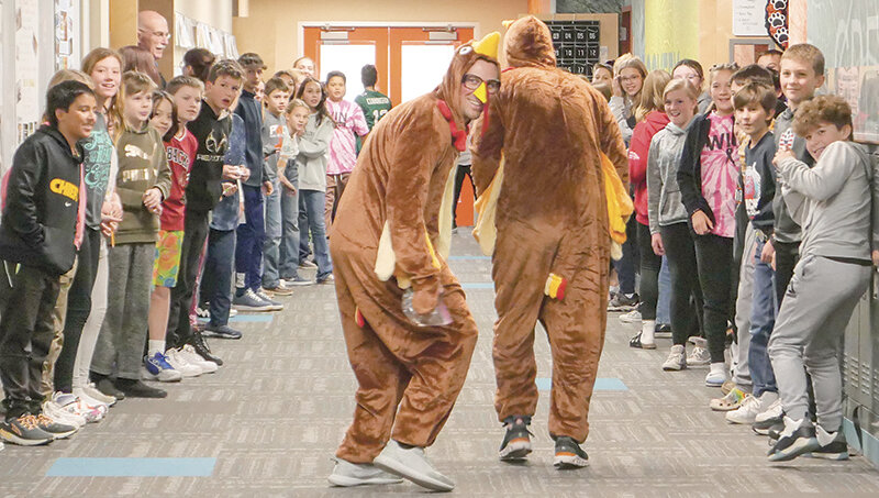 Chanler Buck, the assistant principal at Powell Middle School (left) runs through the school as a turkey alongside Principal Kyle Rohrer. The turkey hunt is a Thanksgiving tradition at Powell Middle School.