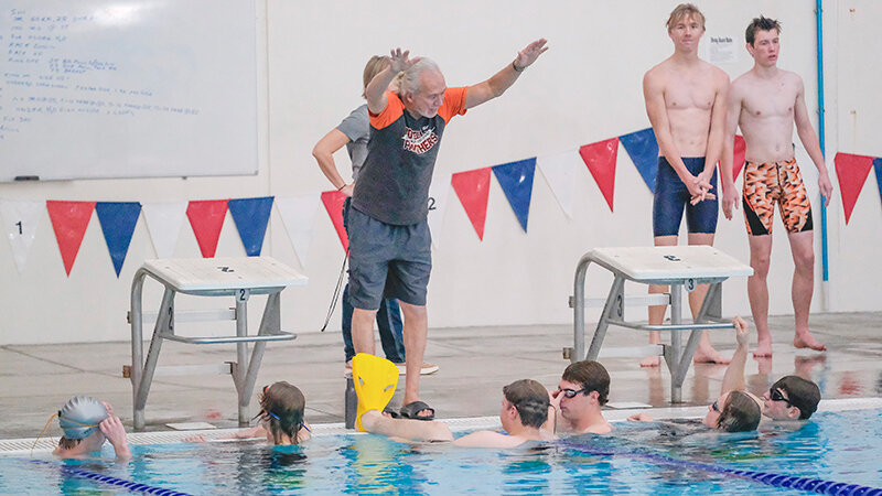 Swimming assistant coach Jerry Rodriguez demonstrates what he wants the swimmers to focus on during a Friday drill.