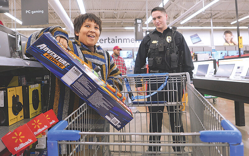 Cervando Vega (left) puts a Nerf gun in his shopping cart while Powell Police Officer Isaac Gutierrez assists.