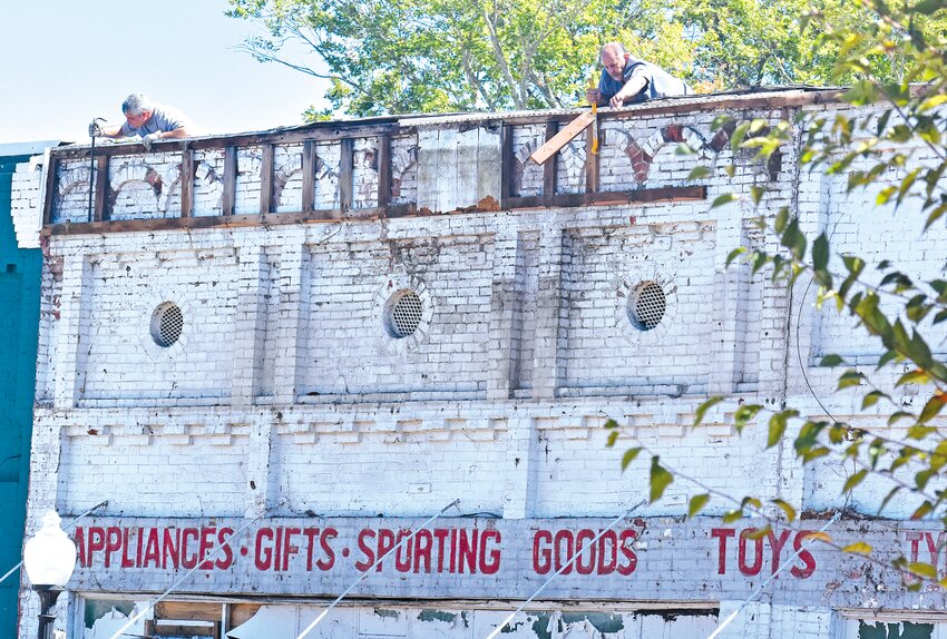 FACE LIFT -  Bill Gilbert, left, and Mark Ward work on removing the facade from the former Hall Hardware building on Saturday morning. Ward and Gilbert are partnering in the renovation project with hopes of opening a retail store and a small event venue in the building.