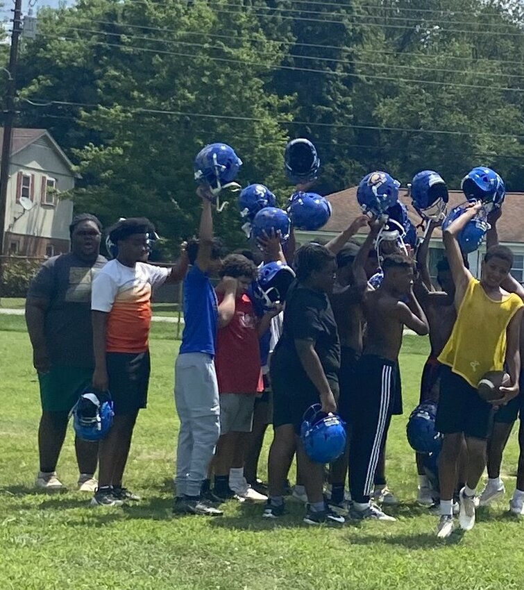 North Side’s freshmen lift their helmets high as they end practice on July 11.