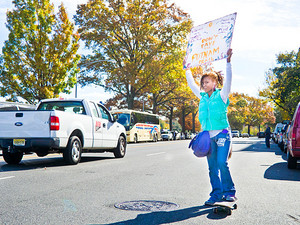 Jackie Powell, 23, rides her skateboard and holds up a &ldquo;don&rsquo;t pave the Putnam Trail&rdquo; sign on Broadway and 251st on Sunday.