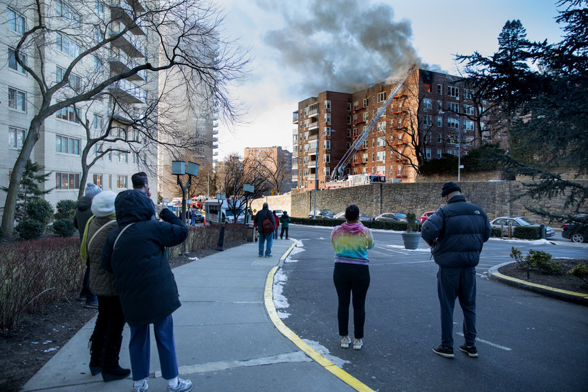 Community members watch as firefighters work to extinguish a three-alarm fire at 601 Kappock St.