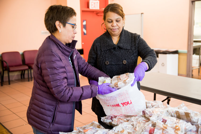 Norma Collado, left, and Carmen Morel pack food for a neighbor at the Kingsbridge Heights Community Center. The organization partnered with celebrity chef Jose Andres&rsquo; World Central Kitchen to serve as a food distribution center in the neighborhood. KHCC has moved quickly to adapt its services to meet the needs of the community during the coronavirus pandemic.