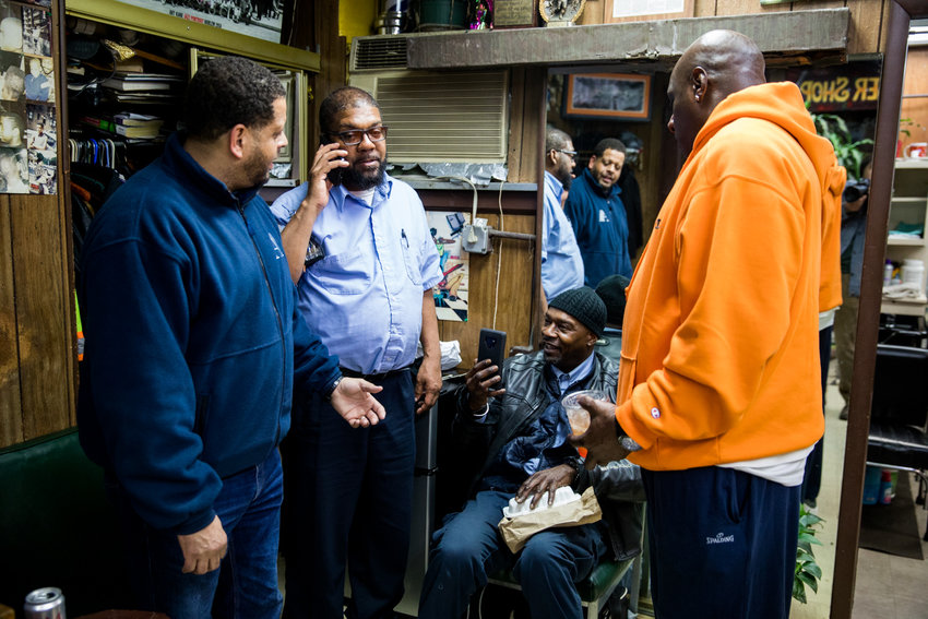 Walter Watson, second from left, talks on the phone inside Marble Hill&rsquo;s International Unisex Salon on March 6, where he was a longtime customer. The MTA bus driver would die from complications related to COVID-19 less than two months later at 55.