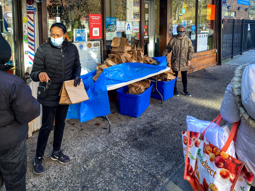 Antonia Feliz works with another volunteer to hand out bags of food in front of Taste &amp; Sabor on West 231st Street to those who might be a little short on food. The restaurant has been lending a helping hand to those in need even before the coronavirus pandemic.