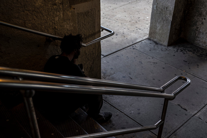 A homeless man sits on the steps of Woodlawn&rsquo;s subway station just a stone's throw from a men's overnight shelter. Some in this part of the Bronx are concerned the city's hasty move to transfer homeless people back to congregate shelters and out of the hotels they stayed in during the height of the coronavirus pandemic may result in more loitering and trespassing issues, disrupting residential and retail neighborhoods.