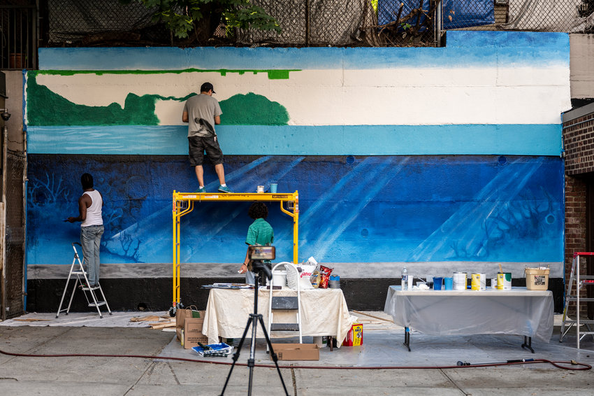 Artist Nicky Enright joins a volunteer painting a mural on the back retaining wall of 3636 Greystone Ave., where he lives. Enright was commissioned to paint this mural, &lsquo;Aquarium,&rsquo; by his building&rsquo;s co-op board because he&rsquo;s no stranger to mural painting.