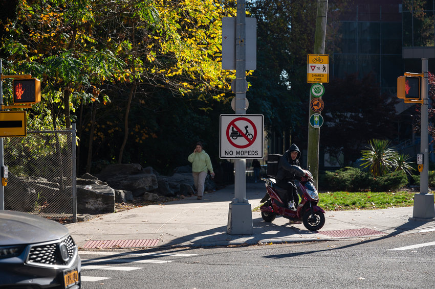 A delivery driver riding a moped on the pathway near Manhattan College&rsquo;s Kelly Commons is oblivious to the &ldquo;No Moped&rdquo; sign that was recently put up there.