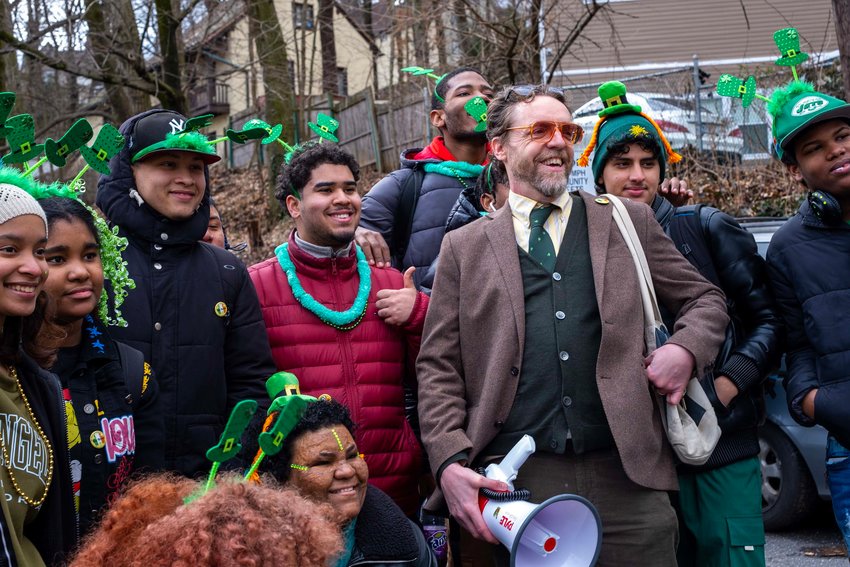 During the annual West 251st Street St. Patrick&rsquo;s Day Parade on March 11 John PL Kelly of Fieldston stands with a contingent of students from English Language Learners and International Support Preparatory Academy located in John F. Kennedy High School. He and his wife, Pamela, have produced the parade the past four years. They had a bag piper and a banner made from rags that 20 neighbors helped assemble. The parade, which attracted 150 people, also drew members of the New York City parks mounted police, city sanitation department and the MTA. The Riverdale Nature Preservancy also had a group of people take part.