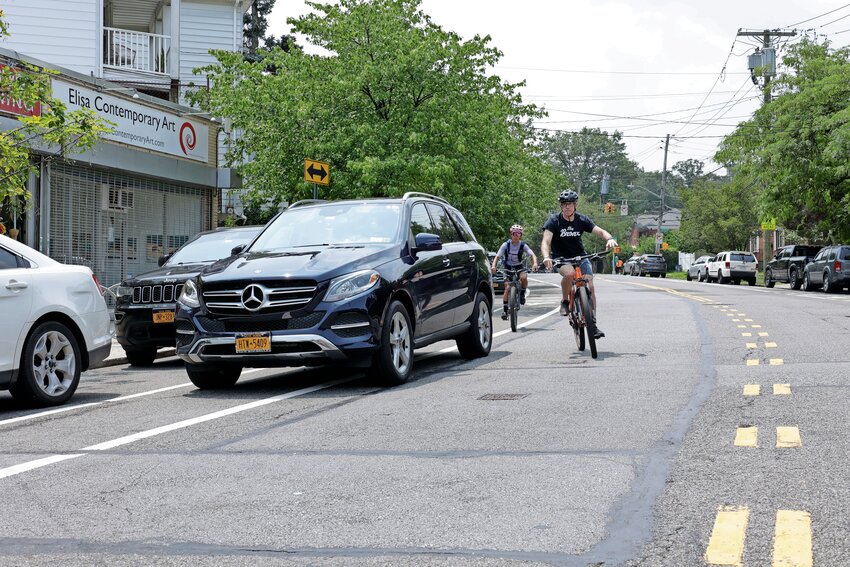Jonathan Cane rides down Mosholu Avenue with his wife avoiding a double-parked car in a designated bike lane. Actually the car was without a driver for approximately 20 minutes, The Riverdale Press witnessed.
