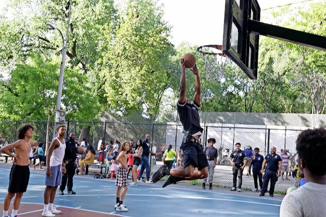 An officer of the 50th Precinct dunks the basketball during a game at the 40th Annual Night out at Bailey Park Tuesday, Aug. 1.