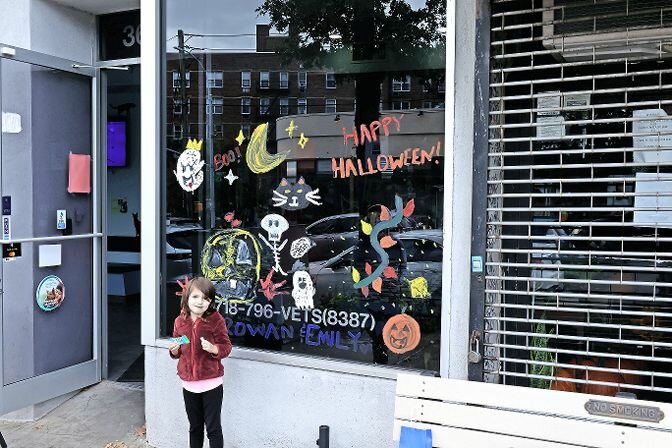 A girl stands outside a decorated window on Johnson Avenue Sunday during the 66th annual Kiwanis Club of Riverdale Halloween Window contest.