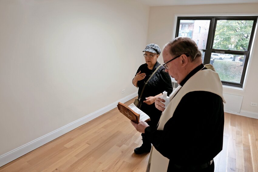 Father Brian McCarthy of St. Margaret of Cortona and St. Gabriel Church blessed Nitza Bravo&rsquo;s renovated apartment on Wednesday, Nov. 15. It was important to put holy water on the spot where nearly three years ago a fire killed her ex-husband, Juan Melendez.