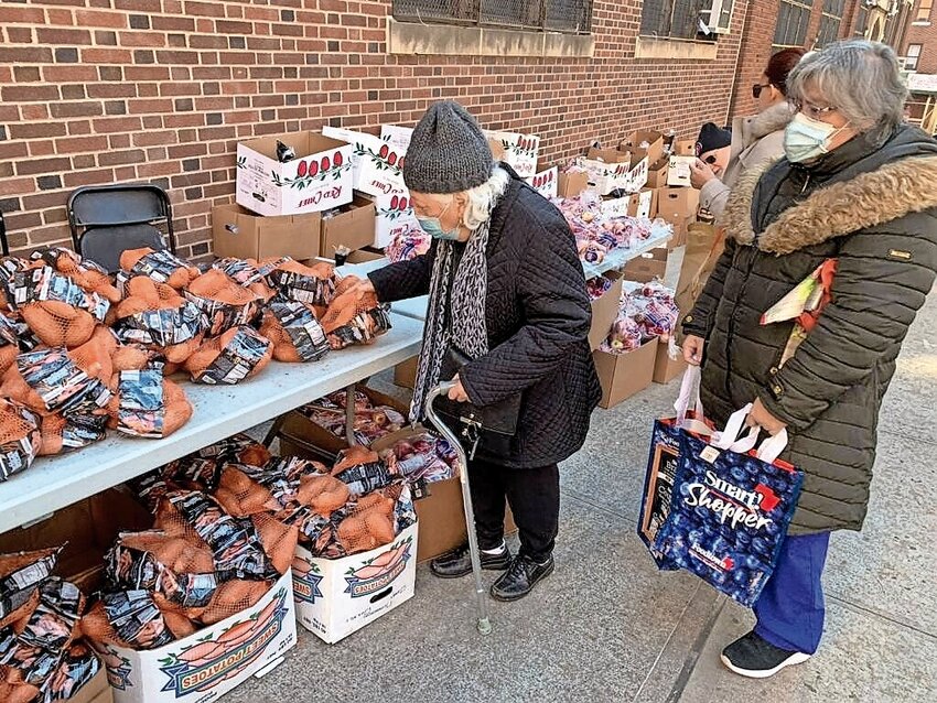 Members of the community get yams and other fresh produce for Thanksgiving outside P.S. 207 Monday. The Riverdale Y and Race-West, a root vegetable distribution business based in Clarks Summit, Pennsylvania that has operated out of Riverdale for 12 years, provided the free produce to residents. 