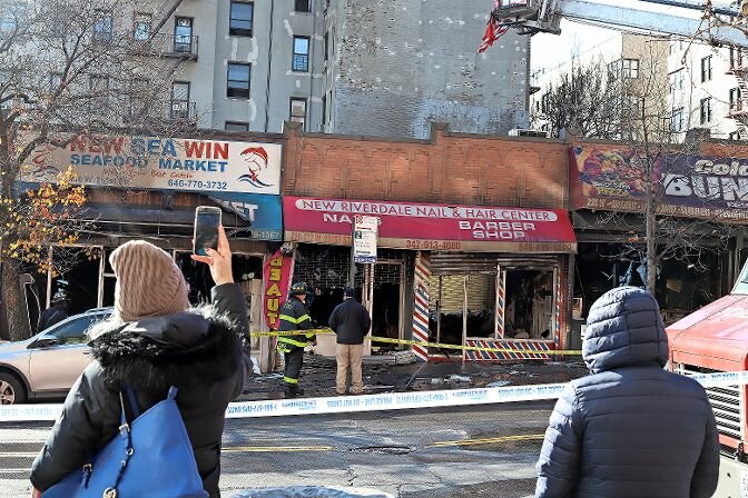 Onlookers watch as firefighters continue to assess the damage to the five storefronts that were destroyed by the five-alarm fire on Dec. 13.
