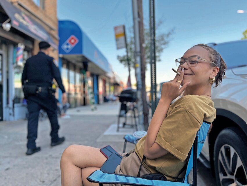 Queens resident Jewely Colon holds up a joint as a 50th Precinct officer walks by Wednesday, May 22. Colon said she is excited about a state licensed dispensary opening at 3633 Kingsbridge Ave.