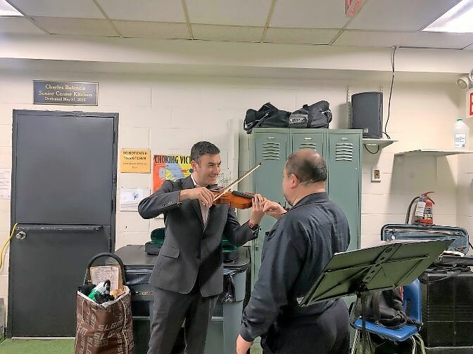 Jorge Avila, award winning violinist, gives an impromptu lesson to Councilman Eric Dinowitz prior to the FY25 budget forum in Norwood.