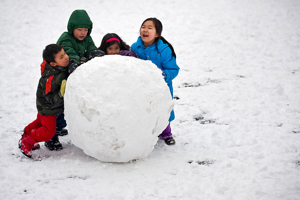From left to right, Joe Michaud, 7, Lawrence Meng, 8, Ellie Michaud, 8, and Katherine Zhou, 8, roll giant snowball across the PS24 schoolyard on Jan. 7.