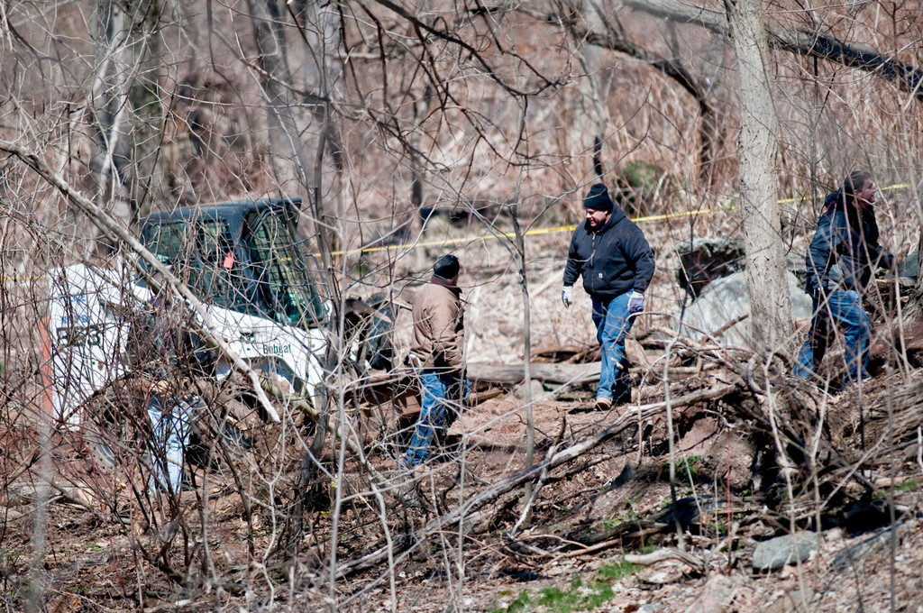 Law enforcement officials use a bobcat to search for a body in Riverdale Park on Tuesday afternoon.