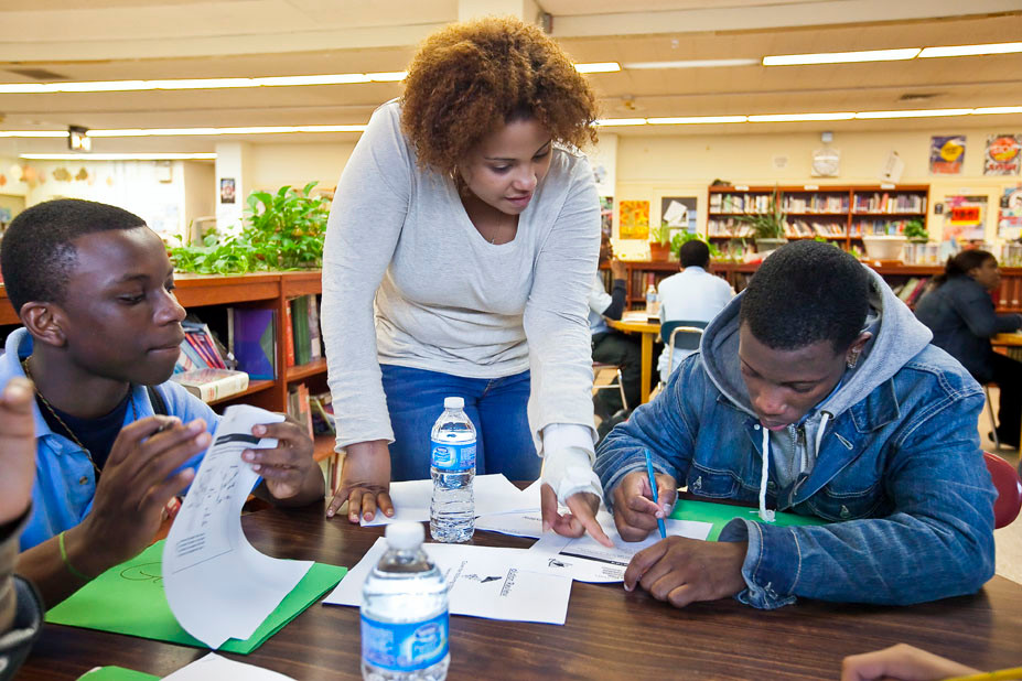 Gilbert Nyantakyi, left, and Dejuane Nicholls, right, both freshman at New Vision Charter High School for Advance Math and SCience, receive living environment instruction on May 9 from Taina Roman, center, a tutor with Manhattan College Optimal Readiness Center.