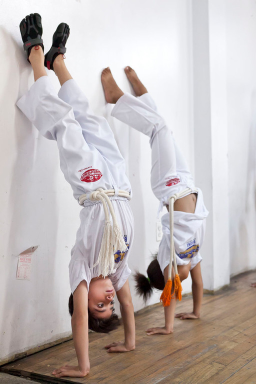 Jorge Ballestero and Ella Gonzalez do a head stand in the Saturday kids capoeira class at Church of the Mediator.