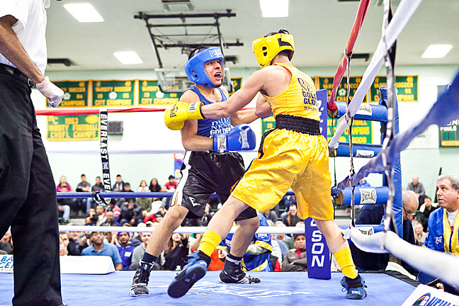 Arnold Gonzales, 19, in blue and black, exchanges blows with his Golden Gloves challenger Joel Lugo, in yellow, at Holy Cross High School in Flushing, Queens on March 7.