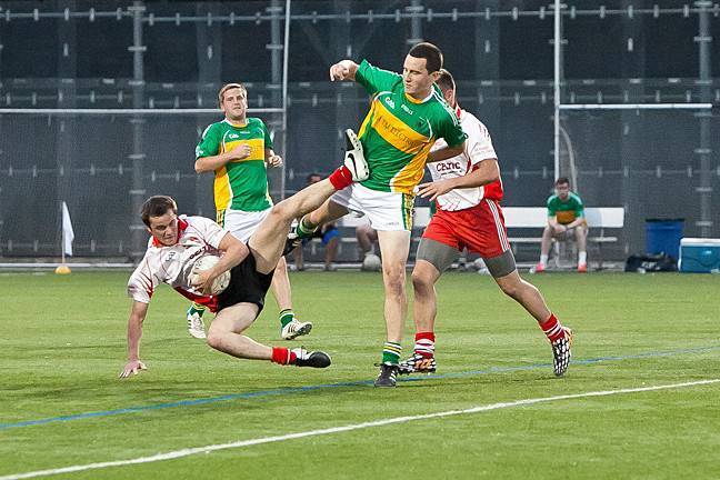 Thomas Wyle, of Tyrone, goes down with the ball as Niall Croke, playing for St. Barnabas, stands nearby at Gaelic Park on July 10.