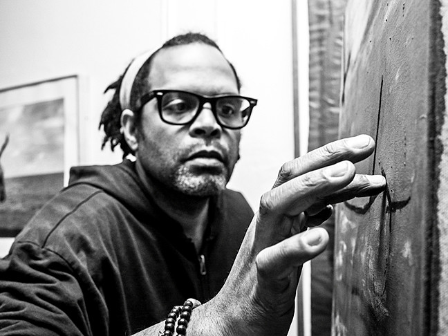 Artist Alexis Mendoza fine tunes a charcoal etching, photographed by Osjua A. Newton.