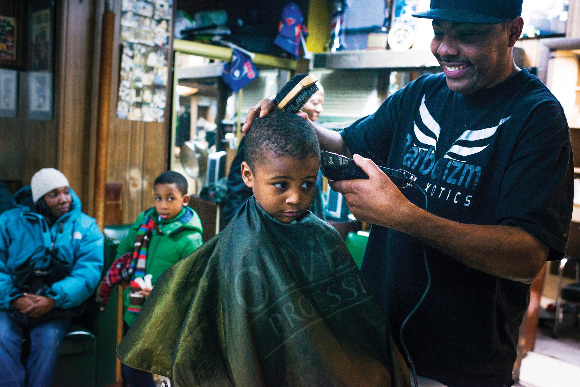 Kawan Shomo, 3, has his hair cut by Garfield Myrie, 43, the shop's second barber. Kawan is the fourth generation Shomo to have his haircut at the barbershop.
