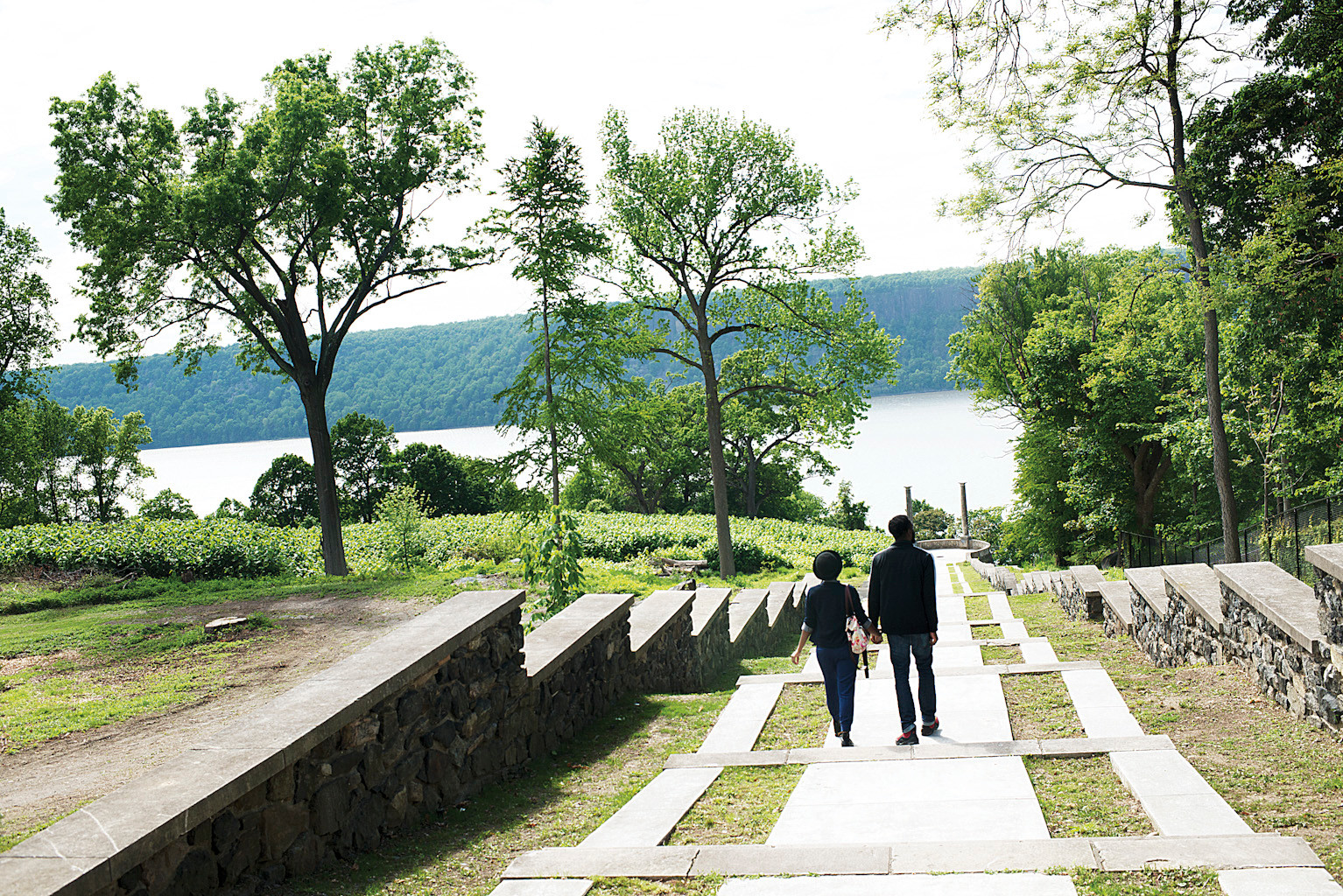 A young couple takes the stairs leading to a viewing platform called the Overlook, offering views of the Hudson River and Palisades.