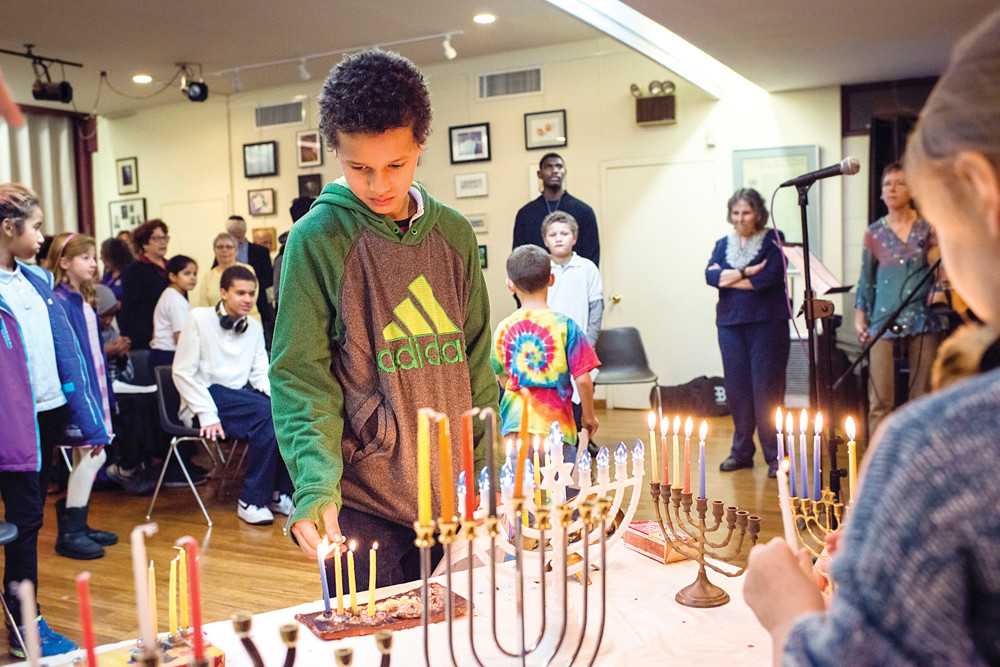 Haqq Coulibably, aged 12, lights a menorah candle during an interfaith gathering at the Society for Ethical Culture in Fieldston on Dec. 9.
