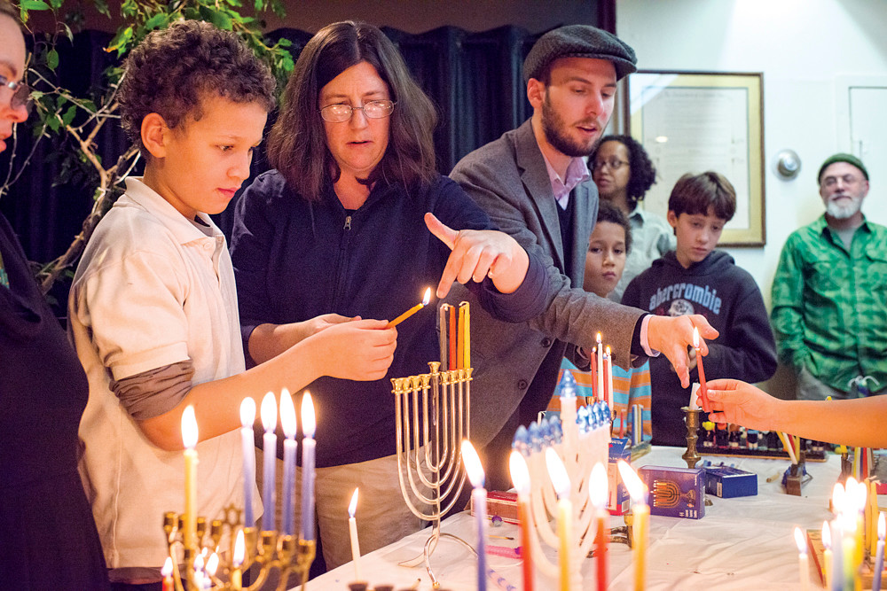 Hamid Coulibably, aged 10, lights a menorah candle during an interfaith gathering at the Society for Ethical Culture in Fieldston on Dec. 9.