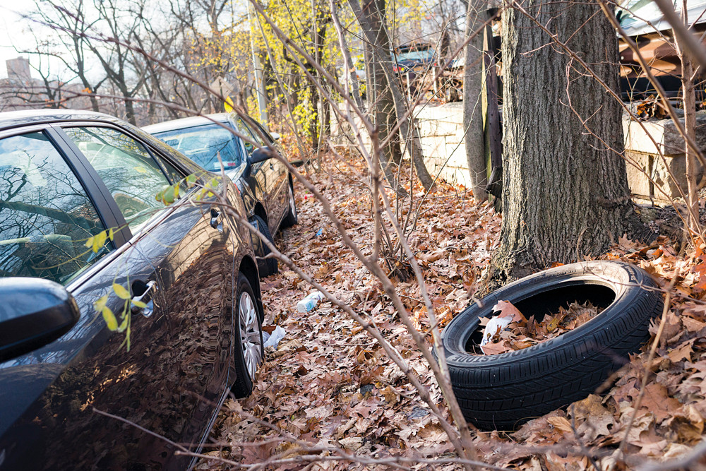Trash and discarded tires line the curb along Manhattan College Parkway at Delafield Avenue, seen on Monday afternoon.