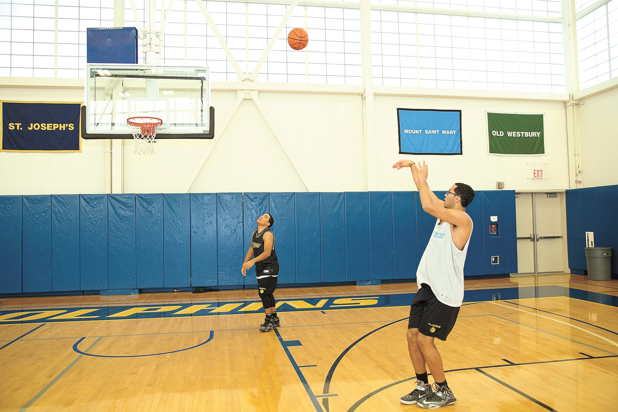 Drew Curiel shoots while Francisco ‘Neeko’ Zeno looks on at the College of Mount St. Vincent gym. The duo runs a youth basketball program called  Be You Stay True.
