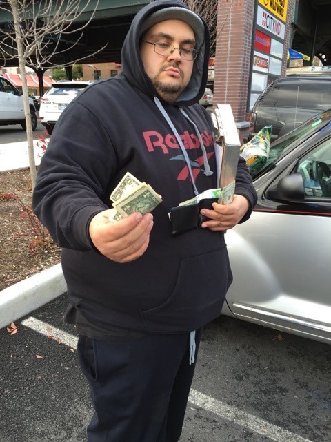 A tow truck operator of the All Boro towing company accepts a cash payment from a driver in the parking lot of a shopping center, in this photo submitted by Nancy Wertsch.